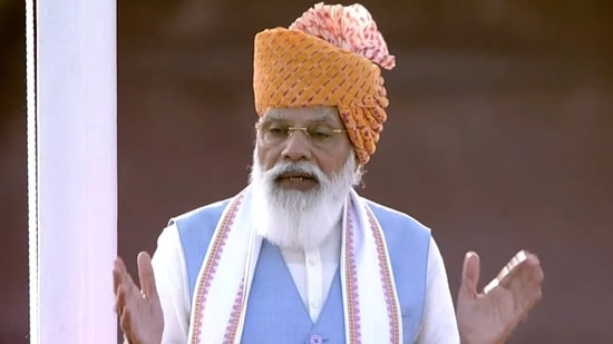 In 2021, Modi continued the tradition of wearing saffron turbans during his Independence Day address. This time, the headgear was adorned with red patterns and a long pink trail. He also wore a white kurta paired with a blue jacket and a white scarf.&nbsp;(File Photo)
