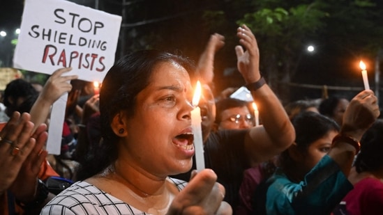 Medical professionals and activists in Kolkata hold posters and candles as they take part in a midnight protest to condemn the rape and murder of a young medic.(AFP)