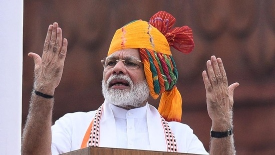 Prime Minister Narendra Modi addressed the nation from the rampart of Red Fort during the 73rd Independence Day in a white kurta set, a printed stole, and a turban with neat multicolour pleats on one side.&nbsp;(Vipin Kumar/HT PHOTO)