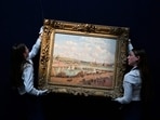 Two members of staff hold the painting by late Franco-Danish painter Camille Pissaro 