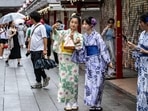 People wearing yukata taking pictures at Sensoji temple in Tokyo's Asakusa district. Japan travel update: Bullet trains and flights resume service after Typhoon Ampil passes, Tokyo beaches remain closed (Photo by Philip FONG/AFP)