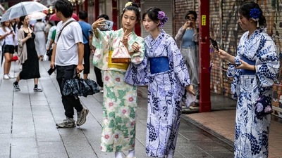 People wearing yukata taking pictures at Sensoji temple in Tokyo's Asakusa district. Japan travel update: Bullet trains and flights resume service after Typhoon Ampil passes, Tokyo beaches remain closed (Photo by Philip FONG/AFP)