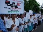 Kolkata rape-murder: Doctors and medical students hold placards and candles during a protest against the rape and killing of a trainee doctor at a government hospital.(AP) Kolkata rape-murder: Doctors and medical students hold placards and candles during a protest against the rape and killing of a trainee doctor at a government hospital.(AP)
