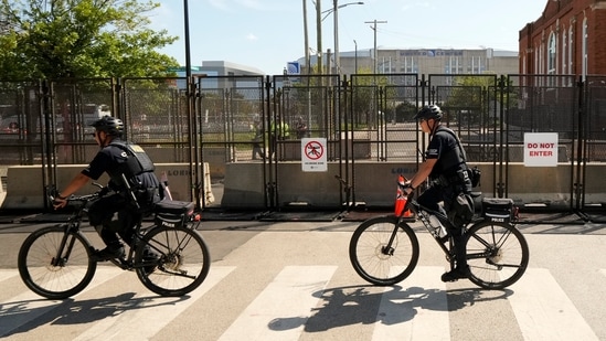 Police officers on bicycles ride past a section of the newly reinforced fence surrounding the United Center at the Democratic National Convention in Chicago on Tuesday, Aug. 20, 2024. (AP Photo/Julio Cortez)(AP)