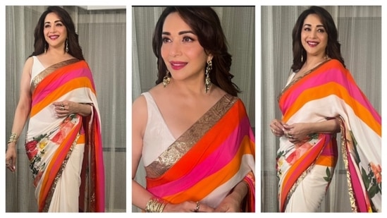Madhuri Dixit wore a white floral saree with vibrant colours of orange, red, and pink as accents. With a shimmering golden border running along the pallu, Madhuri Dixit exuded a timeless glamour. She opted for golden bangles and jhumkas as the accessories. (Instagram/@madhuridixitnene)