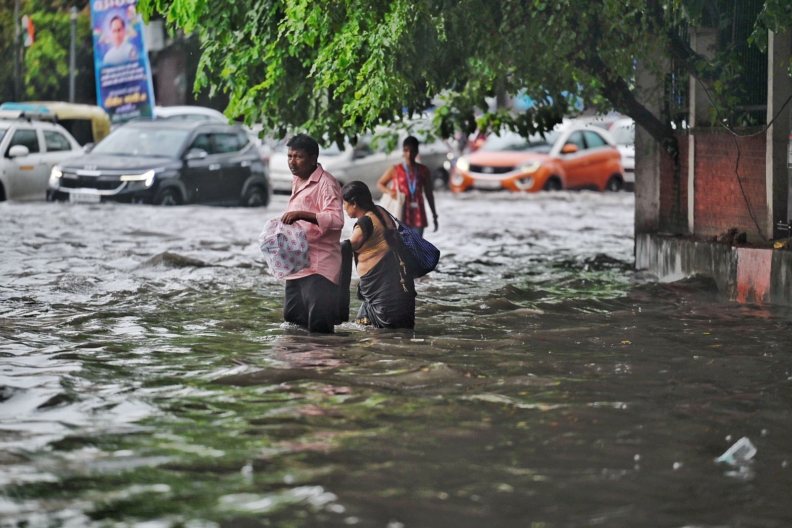 Pedestrians try to wade through waterlogged roads. (Photo by Raj j K Raj / Hindustan Times)