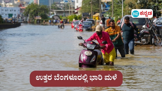 Commuters push their two-wheelers through a waterlogged road after heavy rain, near Kendriya Vihar apartment in Bengaluru on Tuesday