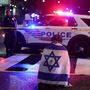 A man, with an Israeli flag with a cross in the center, kneels next to emergency personnel working at the site where, according to the U.S. Homeland Security Secretary, two Israeli embassy staff were shot dead near the Capital Jewish Museum in Washington, D.C., U.S. May 21, 2025.  REUTERS/Jonathan Ernst    TPX IMAGES OF THE DAY