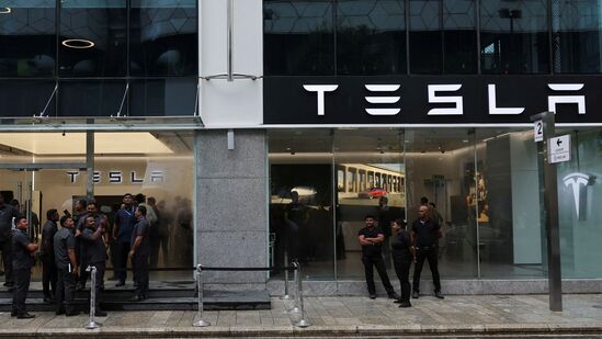 People are seen outside the Tesla showroom ahead of its opening in Mumbai.