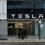 People are seen outside the Tesla showroom ahead of its opening in Mumbai.