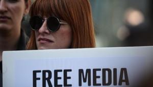 A journalist holds a placard reading A journalist holds a placard reading