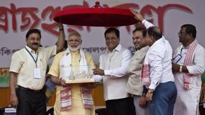 Prime Minister Narendra Modi receives a memento from Assam chief minister Sarbananda Sonowal as BJP workers hold an Assamese Japi, a traditional headgear, in Guwahati on Friday.(AP) Prime Minister Narendra Modi receives a memento from Assam chief minister Sarbananda Sonowal as BJP workers hold an Assamese Japi, a traditional headgear, in Guwahati on Friday.(AP)