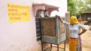 A woman stands near the official writing on the wall outside her home in Pilodi in Dausa.(Prabhakar Sharma / HT Photo)