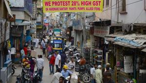 Pedestrians walk below a banner calling for a protest against the steep hike in the proposed new goods and services tax (GST) regime for sanitary and hardware products in Bangalore on June 29, 2017.(AFP) Pedestrians walk below a banner calling for a protest against the steep hike in the proposed new goods and services tax (GST) regime for sanitary and hardware products in Bangalore on June 29, 2017.(AFP)