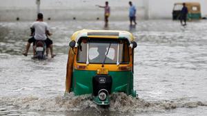 An auto-rickshaw moves through a waterlogged road after heavy rain in Ahmedabad.(REUTERS) An auto-rickshaw moves through a waterlogged road after heavy rain in Ahmedabad.(REUTERS)