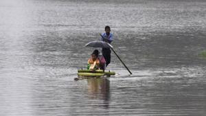 Villagers travel on a raft through flood waters in Hatilung village in Lakhimpur district, about 380 km from Guwahati, in Assam on Saturday.(AFP) Villagers travel on a raft through flood waters in Hatilung village in Lakhimpur district, about 380 km from Guwahati, in Assam on Saturday.(AFP)