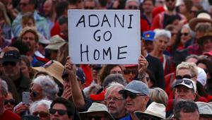 A protester holds a sign as he participates in a national Day of Action against Adani's planned coal mine at Sydney's Bondi Beach in Australia.(Reuters Photo) A protester holds a sign as he participates in a national Day of Action against Adani's planned coal mine at Sydney's Bondi Beach in Australia.(Reuters Photo)