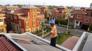 A worker cleans solar panels at a solar housing complex near Kolkata. For curbing the environmental impact of buildings, electrical demand reduction needs to be supported by electricity generation from green sources.(AFP file) A worker cleans solar panels at a solar housing complex near Kolkata. For curbing the environmental impact of buildings, electrical demand reduction needs to be supported by electricity generation from green sources.(AFP file)