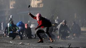 A Palestinian protester uses a sling to hurl stones towards Israeli troops during clashes as Palestinians call for a A Palestinian protester uses a sling to hurl stones towards Israeli troops during clashes as Palestinians call for a