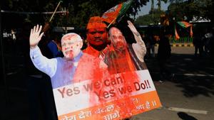 A BJP supporter holds a placard as he celebrates outside the party headquarters in New Delhi on December 18.(AFP Photo) A BJP supporter holds a placard as he celebrates outside the party headquarters in New Delhi on December 18.(AFP Photo)