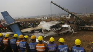 Nepalese rescuers and police near the debris of a passenger plane from Bangladesh that crashed at the airport in Kathmandu on March 12.(AP) Nepalese rescuers and police near the debris of a passenger plane from Bangladesh that crashed at the airport in Kathmandu on March 12.(AP)
