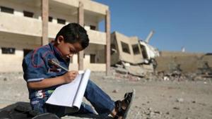 A Yemeni boy school writes as he sits outside a school on March 16, 2017, that was damaged in an air strike in the southern Yemeni city of Taez.(AFP) A Yemeni boy school writes as he sits outside a school on March 16, 2017, that was damaged in an air strike in the southern Yemeni city of Taez.(AFP)