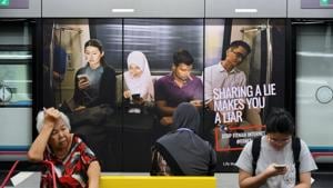Commuters sit in front of an advertisement discouraging the dissemination of fake news, at a train station in Kuala Lumpur, Malaysia, on March 28.(Reuters File Photo) Commuters sit in front of an advertisement discouraging the dissemination of fake news, at a train station in Kuala Lumpur, Malaysia, on March 28.(Reuters File Photo)