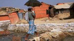 A Rohingya refugee carries his child across a bamboo bridge in Balukhali refugee camp, in Cox's Bazar, Bangladesh.(Reuters) A Rohingya refugee carries his child across a bamboo bridge in Balukhali refugee camp, in Cox's Bazar, Bangladesh.(Reuters)