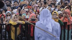 People use their mobile phones to take pictures as a Sharia law official whips a woman who is convicted of prostitution during a public caning outside a mosque in Banda Aceh, Indonesia.(AP Photo)