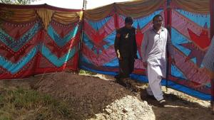 Pakistani policemen walk beside the grave of Italian national of Pakistani origin Sana Cheema, who was allegedly killed by her family members, in Gujrat of Pakistan's Punjab province on April 25.(AFP Photo)