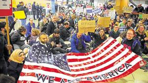 Demonstrators sit in the concourse at Seattle-Tacoma International Airport in Seattle, Wash., with a sign that reads Demonstrators sit in the concourse at Seattle-Tacoma International Airport in Seattle, Wash., with a sign that reads