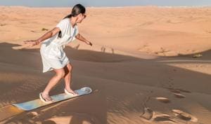 A young woman sand boarding in the Dubai desert.(Shutterstock) A young woman sand boarding in the Dubai desert.(Shutterstock)