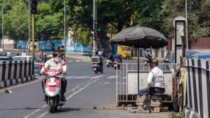 A traffic warden sits under the cover of an umbrella in the scorching heat as a commuter passes by near Sangamwadi on Tuesday.(Sanket Wankhade) A traffic warden sits under the cover of an umbrella in the scorching heat as a commuter passes by near Sangamwadi on Tuesday.(Sanket Wankhade)