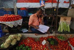 A vendor speaks on his mobile phone as he maintains his ledger book at a stall selling vegetables in Mumbai.(Reuters) A vendor speaks on his mobile phone as he maintains his ledger book at a stall selling vegetables in Mumbai.(Reuters)