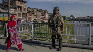 A paramilitary soldier stands guard as a Kashmiri woman walks past in Srinagar on June 20.(AP) A paramilitary soldier stands guard as a Kashmiri woman walks past in Srinagar on June 20.(AP)