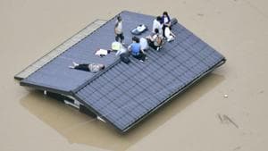 An aerial view shows local residents seen on the roof of submerged house at a flooded area as they wait for a rescue in Kurashiki, southern Japan on July 7.(Kyodo/via REUTERS)