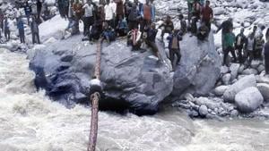 A villager crosses the river by crawling over a tree trunk as others hold it in place.(HT Photo) A villager crosses the river by crawling over a tree trunk as others hold it in place.(HT Photo)