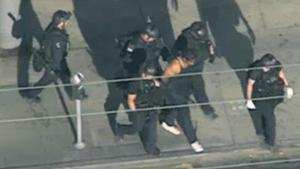 In this image from video provided by KNBC-TV, police officers escort a suspect away from a Trader Joe's supermarket in the Silver Lake district of Los Angeles on Saturday after a more than three hour standoff.(AP) In this image from video provided by KNBC-TV, police officers escort a suspect away from a Trader Joe's supermarket in the Silver Lake district of Los Angeles on Saturday after a more than three hour standoff.(AP)