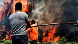 Firefighters and volunteers try to extinguish flames during a wildfire at the village of Kineta, near Athens, on July 24.(AFP Photo) Firefighters and volunteers try to extinguish flames during a wildfire at the village of Kineta, near Athens, on July 24.(AFP Photo)
