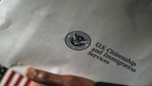 A man holds an envelope from the US Citizenship and Immigrations Service in Washington.(REUTERS) A man holds an envelope from the US Citizenship and Immigrations Service in Washington.(REUTERS)