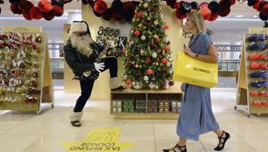 A shopper walks past an actor dressed as Rock and Roll Santa, at the launch of the Christmas shop at Selfridges store in London.(AP) A shopper walks past an actor dressed as Rock and Roll Santa, at the launch of the Christmas shop at Selfridges store in London.(AP)