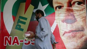 A man walks past an image of cricket star-turned-politician Imran Khan, chairman of Pakistan Tehreek-e-Insaf (PTI) at a market in Islamabad, Pakistan, July 27, 2018.(REUTERS) A man walks past an image of cricket star-turned-politician Imran Khan, chairman of Pakistan Tehreek-e-Insaf (PTI) at a market in Islamabad, Pakistan, July 27, 2018.(REUTERS)