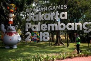 FILE PHOTO: A worker cleans near a sign for the upcoming 2018 Asian Games, which would be held in both Jakarta and Palembang, Sumatra, in Jakarta, Indonesia September 17, 2017.