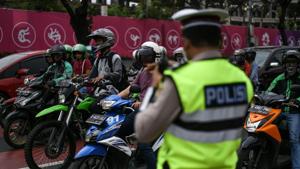 An Indonesian policeman (R) stands next to a traffic light ahead of the 2018 Asian Games in Jakarta on August 17, 2018. - A police crackdown on petty crime in the run-up to the Asian Games in Indonesia has claimed dozens of lives, Amnesty International said on August 17, criticising what it said was an "unnecessary and excessive" campaign.(AFP Photo) An Indonesian policeman (R) stands next to a traffic light ahead of the 2018 Asian Games in Jakarta on August 17, 2018. - A police crackdown on petty crime in the run-up to the Asian Games in Indonesia has claimed dozens of lives, Amnesty International said on August 17, criticising what it said was an "unnecessary and excessive" campaign.(AFP Photo)