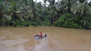 A group of residents cross flooded waters on an inflated tube in Kozhikode district.(AFP)