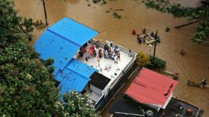 People wait to be rescued atop their house in a flooded region of southern Kerala on Friday.(REUTERS Photo) People wait to be rescued atop their house in a flooded region of southern Kerala on Friday.(REUTERS Photo)