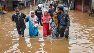 People wade across a waterlogged street after being rescued from flood-affected regions following heavy monsoon rainfall in Kochi.(PTI Photo) People wade across a waterlogged street after being rescued from flood-affected regions following heavy monsoon rainfall in Kochi.(PTI Photo)