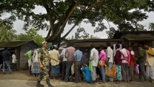 A paramilitary person walks past as people whose names were left out in the National Register of Citizens (NRC) draft stand in a queue to collect forms to file appeals near a NRC center on the outskirts of Guwahati on August 13.(AP Photo) A paramilitary person walks past as people whose names were left out in the National Register of Citizens (NRC) draft stand in a queue to collect forms to file appeals near a NRC center on the outskirts of Guwahati on August 13.(AP Photo)