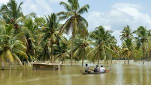 Men take a small boat to travel across flood waters past a marooned farm building to reach their homes in Pandanad in Alappuzha district in Kerala on August 21.(AFP Photo) Men take a small boat to travel across flood waters past a marooned farm building to reach their homes in Pandanad in Alappuzha district in Kerala on August 21.(AFP Photo)