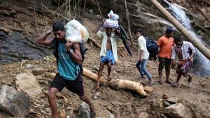 Flood victims carry relief material as they walk through a damaged area after floods, at Nelliyampathy village in Kerala on August 21.(REUTERS) Flood victims carry relief material as they walk through a damaged area after floods, at Nelliyampathy village in Kerala on August 21.(REUTERS)